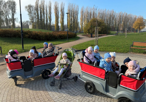 Dzieci jadą we wózkach na jesienny spacer.