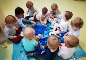 Dzieci bawią się ryżem, przesypują do kubeczków i miseczek.