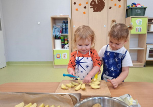 Zosia i Jagna smarują pokrojone ziemniaki masłem.