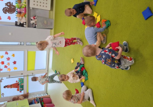 Dzieci bawią się na dywanie woreczkami gimnastycznymi.