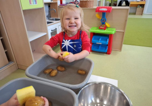 Róża myje ziemniaki w misce z wodą za pomocą gąbki.