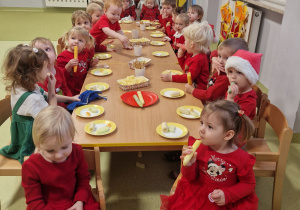 Dzieci siedzą przy stole i świętują Mikołajki.