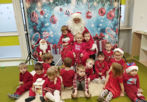 Dzieci pozują do pamiątkowego zdjęcia ze Świętym Mikołajem.
