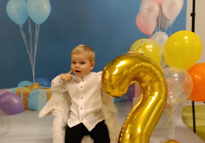 Kuba z balonem w kształcie cyfry 2 pozuje do urodzinowego zdjęcia.