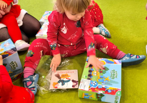 Antosia siedzi na dywanie i ogląda swój prezent, który dostała od Św. Mikołaja.