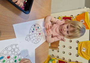 Julia dekoruje bombkę kolorową plasteliną.