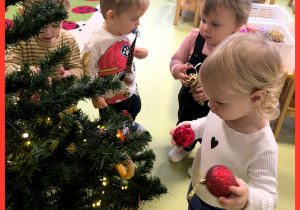 Dzieci wspólnie ubierają choinkę.