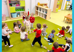 Dzieci biegają po dywanie i rzucają się kulkami z papieru. Bawią się w rzucanie śnieżkami.