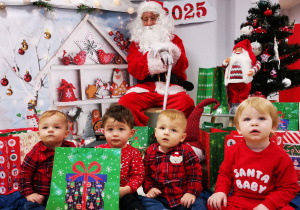 Dzieci pozują z prezentami i Mikołajem.