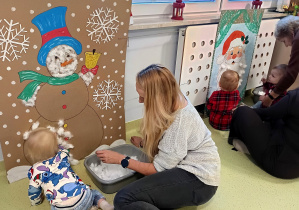 Leon z mamą przykleja kulki waty do dużego bałwanka.