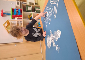 Zosia maluje paluszkiem zimowy pejzaż.