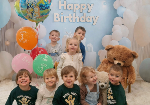 Dzieci pozują do pamiątkowego zdjęcia z okazji urodzin Oliwki.