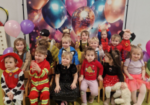 Wszystkie dzieci z grupy Pszczółki pozują do zdjęcia na tle z balonami.