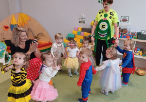 Dzieci tańczą z opiekunkami w kole przy muzyce karnawałowej.