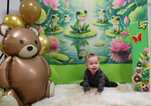 Leoś leży na kocyku na brzuchu, pozuje do urodzinowego zdjęcia.