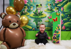 Leoś siedzi na kocyku, pozuje do urodzinowego zdjęcia.