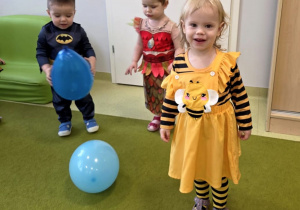 dzieci tańczą na dywanie z kolorowymi balonami.