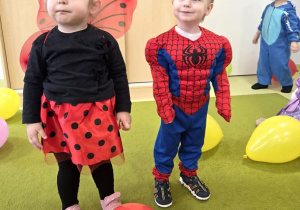 dzieci tańczą na dywanie z kolorowymi balonami.