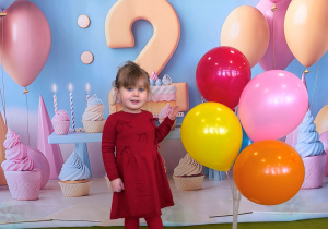 Małgosia pozuje do urodzinowego zdjęcia z kolorowymi balonami.