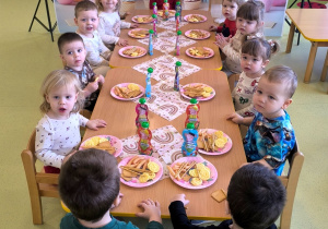 Małgosia i dzieci siedzą przy stole i jedzą słodki poczęstunek.