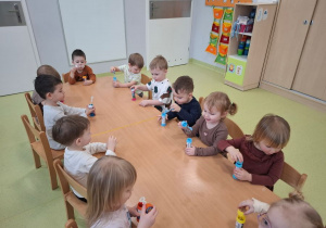 Dzieci puszczają bańki siedząc przy stoliku.