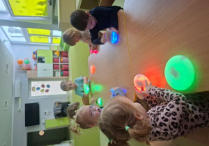 Dzieci przyglądają się kolorowym, świecącym kamieniom.