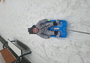 Ignaś pozuje do zdjęcia podczas jazdy na sankach.