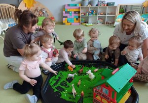 Dzieci bawią się ryżem i zwierzętami gospodarskimi.
