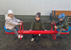Aniela, Antoni i Maksymilian bujają się na huśtawce.
