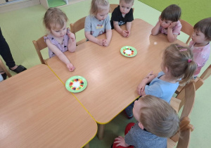 Dzieci obserwują przebieg eksperymentu z wykorzystaniem kolorowych cukierków.