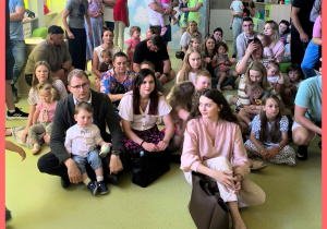 Dzieci razem z rodzicami czekają na prezentację z okazji Dnia Mamy i Taty.