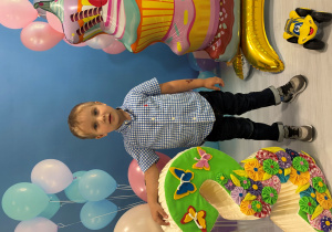 Jakub pozuje do urodzinowego zdjęcia z balonami.