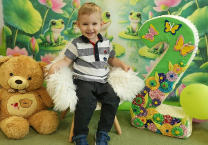 Filip siedzi na krzesełku i pozuje do urodzinowego zdjęcia.
