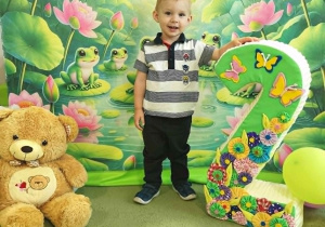 Filip stoi obok dużej cyfry dwa i pozuje do pamiątkowego zdjecia.