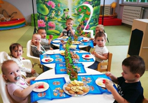 Filip siedzi razem z dziećmi przy urodzinowym stole.