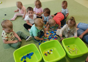 Dzieci uczą się segregować przedmioty według różnych cech wykorzystując miski, korki, spinacze i klocki.