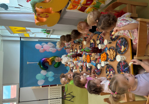 Dzieci siedzą przy stole i jedzą urodzinowy poczęstunek Nikodema.