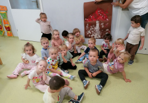 Dzieci siedzą i prezentują wykonanego wspólnie muchomora za pomocą farb.