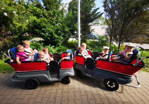 Dzieci siedzą w wózkach wieloosobowych podczas spaceru.